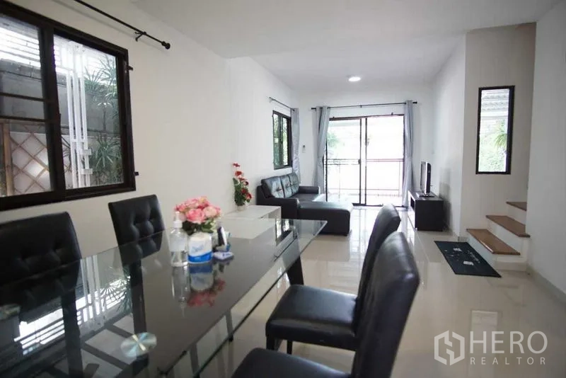 Townhouse for rent in Suan Luang, Bangkok - Long open-plan living–dining space with stairs and front balcony doors.