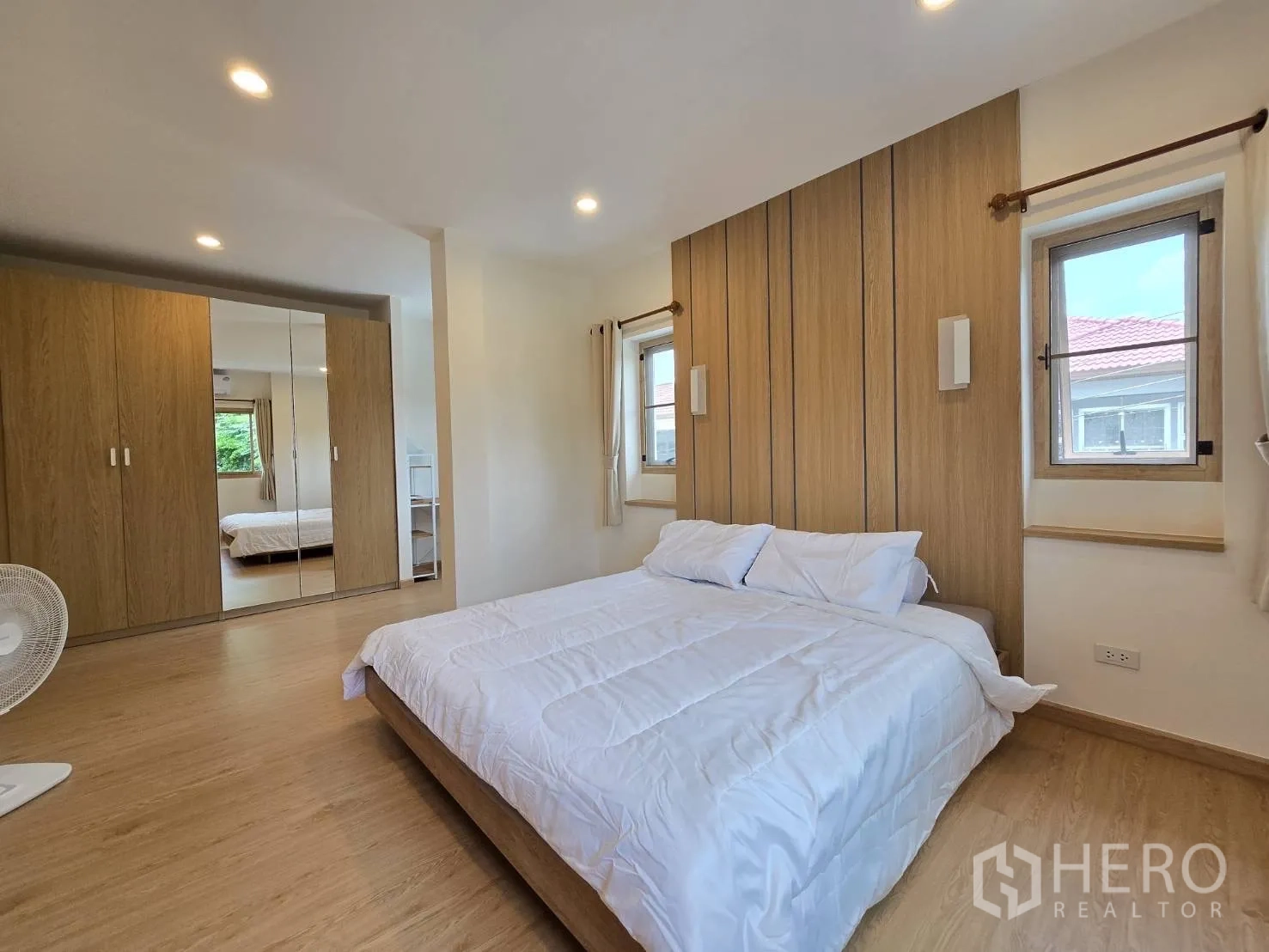Detached House for sale in Suan Luang, Bangkok - Primary bedroom with wood-paneled feature wall and mirrored wardrobes.