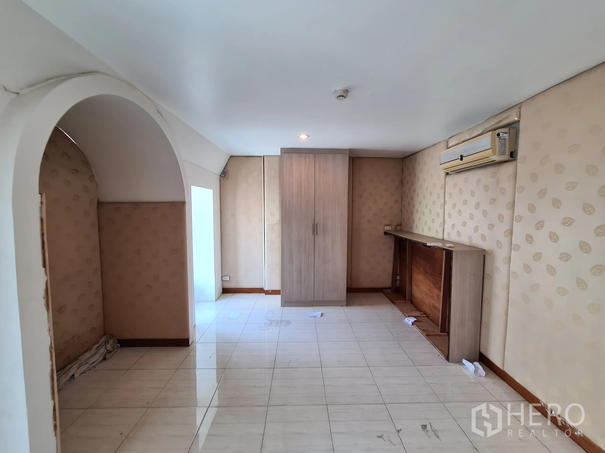 Shophouse for rent or sale in Sathon, Bangkok - Room with arched niche, tiled floor, built-in cabinet and wall air-conditioner.