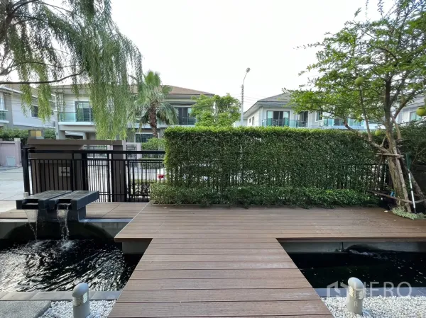 独立式住宅 出租在Suan Luang, Bangkok - 前院木平台与装饰水景，望向街区。