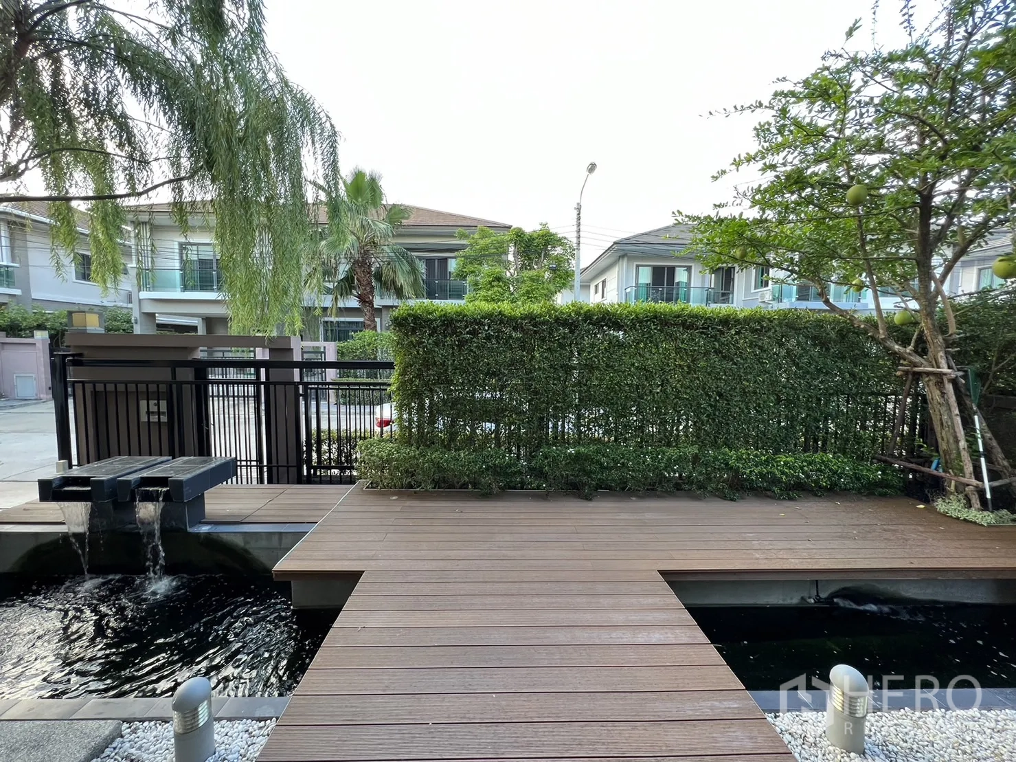 独立式住宅 出租在Suan Luang, Bangkok - 前院木平台与装饰水景，望向街区。