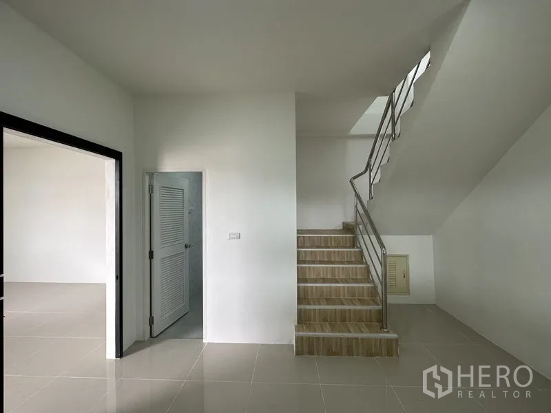 Warehouse for rent in Lam Luk Ka, Pathum Thani - Staircase with stainless handrail next to a bathroom door inside the office area.