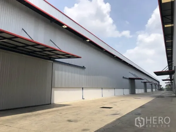 Factory for rent or sale in Phra Nakhon Si Ayutthaya - Long facade of the warehouse showing canopies over loading bays and clear access.