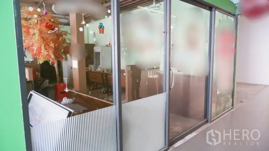 Retail Space for rent in Watthana, Bangkok - Shopfront view showing floor-to-ceiling glass panels and interior seating visible from the corridor.
