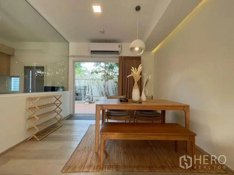 Townhouse for rent in Prawet, Bangkok - Dining area with wooden table, pendant light, and door to terrace