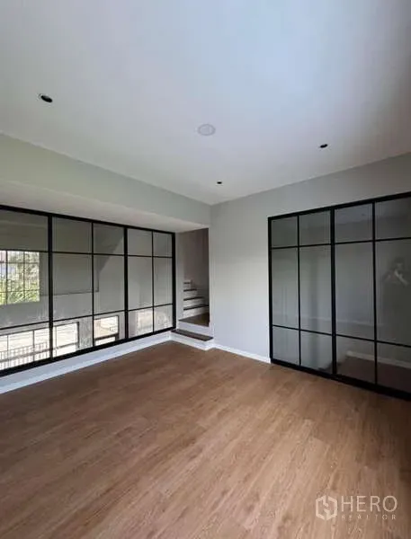 Townhouse for rent or sale in Prawet, Bangkok - Bright room with wood flooring and full-height grid windows.
