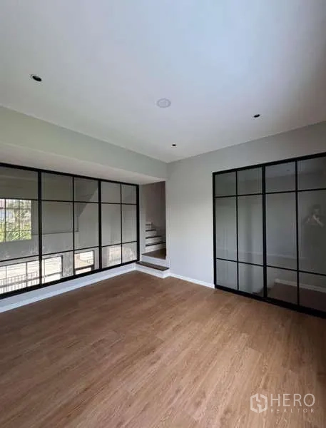 Townhouse for rent or sale in Prawet, Bangkok - Bright room with wood flooring and full-height grid windows.