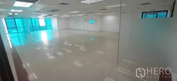 Office Space for rent in Huai Khwang, Bangkok - Open-plan office with glossy tiled floors, drop ceiling lighting, glass partition and blue-tinted windows with city views.