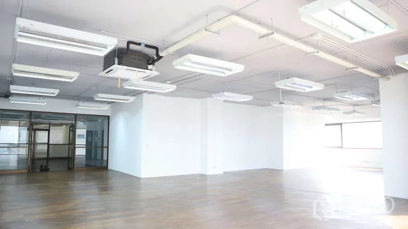 Office Space for rent - Ceiling view of suspended lighting and cassette AC above a large office with glass entry doors.