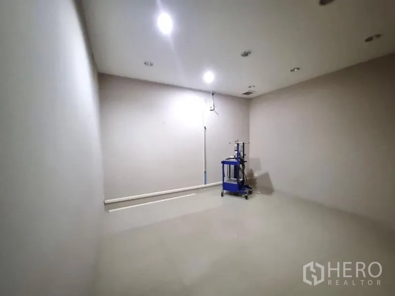 Shophouse for rent in Watthana, Bangkok - Large empty room with spotlights and a single wheeled machine.