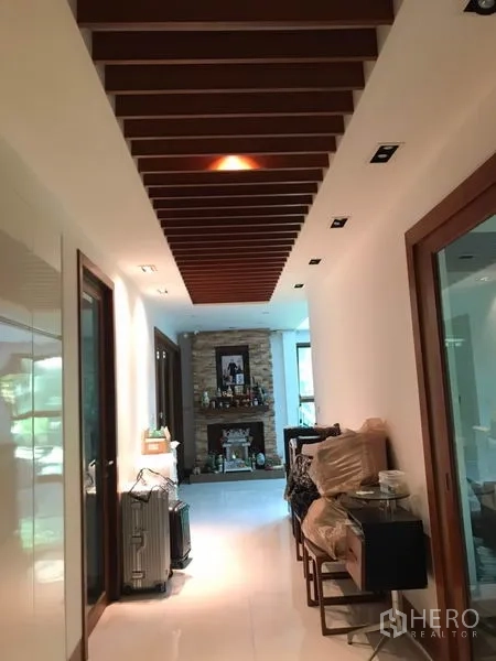 Detached House for sale in Lat Phrao, Bangkok - Bright hallway with slatted wood ceiling, recessed lighting and glass doors leading to rooms.
