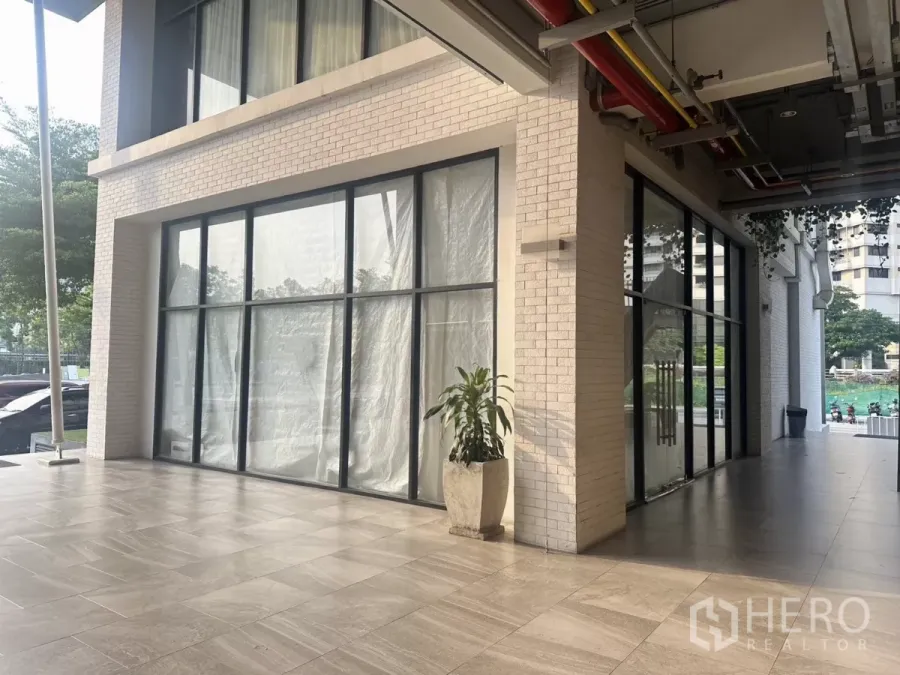 Retail Space for rent in Khlong Toei, Bangkok - Corner ground-floor retail frontage with floor-to-ceiling glass, covered walkway and tiled forecourt.