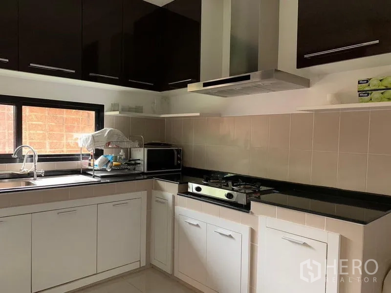 Detached House for rent or sale in Khan Na Yao, Bangkok - Fitted kitchen with gas hob, range hood, black countertops and white cabinets.