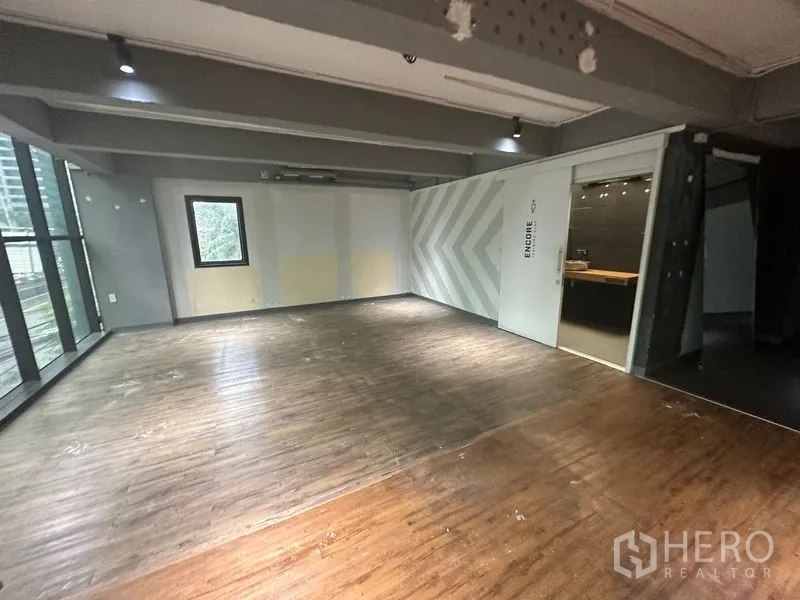 Office Space for rent in Bang Rak, Bangkok - Corner workspace with wood floors, accent chevron wall, and sliding door to a glass-front meeting room.