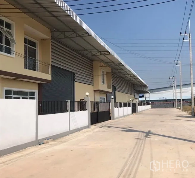 Warehouse for rent in Samut Sakhon - Street view of a row of warehouses with fences and wide concrete access road.
