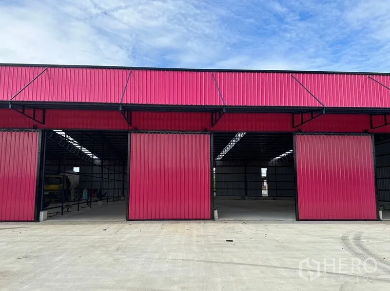 Warehouse for rent in Ban Pho, Chachoengsao - Front elevation of the warehouse with multiple wide red sliding doors for truck loading bays.