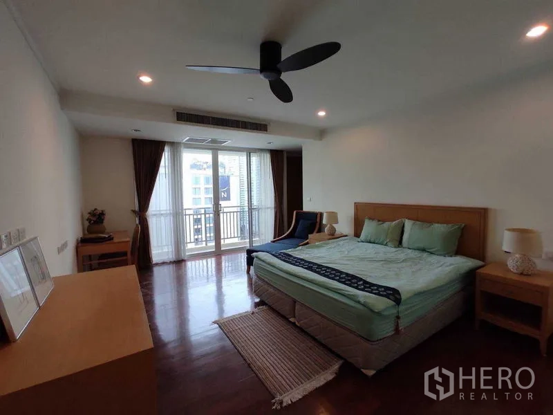 Condominium for rent in Khlong Toei, Bangkok - Bedroom with king bed, ceiling fan and sliding doors to a balcony overlooking the city.