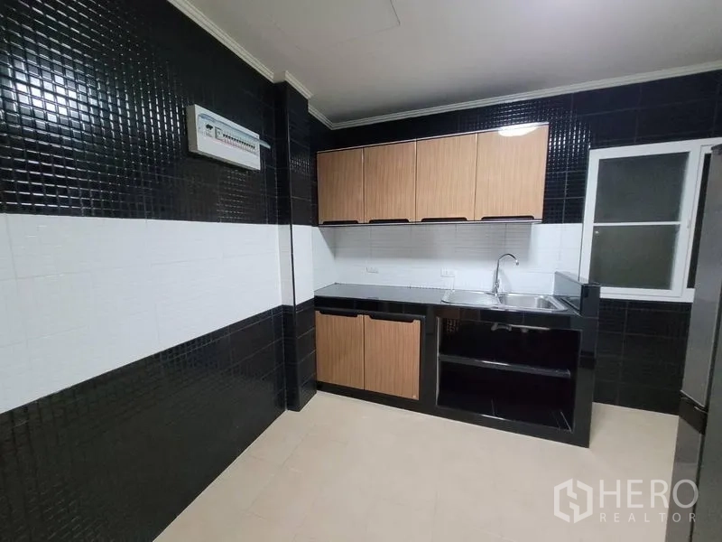 Detached House for rent - Fitted kitchen with black-and-white tiled walls, wood cabinets and stainless sink.