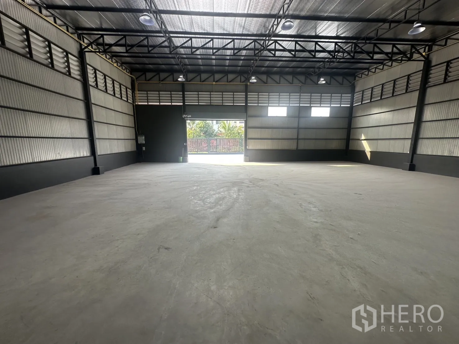 Warehouse for rent in Prawet, Bangkok - Open clear-span warehouse facing the loading door with high-bay lights and ventilation panels.