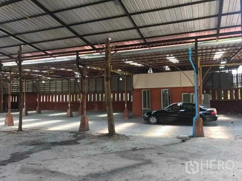Warehouse for rent or sale in Khlong Sam Wa, Bangkok - Warehouse interior showing steel truss roof, hanging lights and a brick ventilation wall.