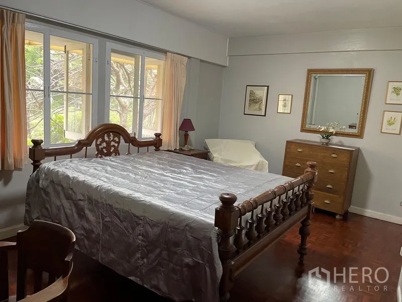 Condominium for rent in Watthana, Bangkok - Bedroom featuring a carved wooden bed, large windows and parquet floor.