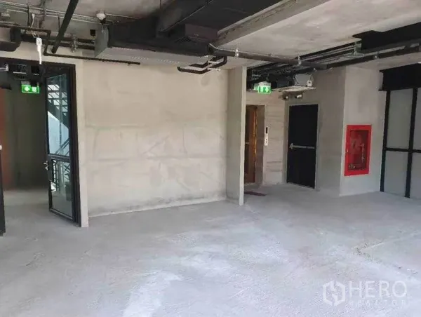 Retail Space for rent in Watthana, Bangkok - Interior corridor with lift, fire exit and red fire hose cabinet inside unfinished space.