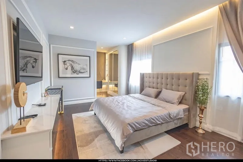 บ้าน ขายในPak Kret, Nonthaburi - ห้องนอนผู้เข้าพักสว่างไสว เตียงบุผ้า ผนังทีวี และทางเข้าเชื่อมห้องน้ำ