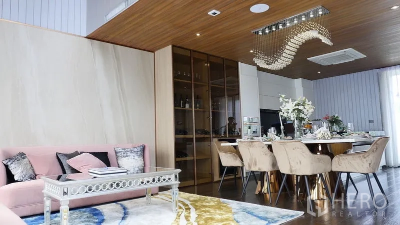 Detached House for sale in Prawet, Bangkok - Stylish lounge and dining space with chandelier, display cabinet and pink sofa.