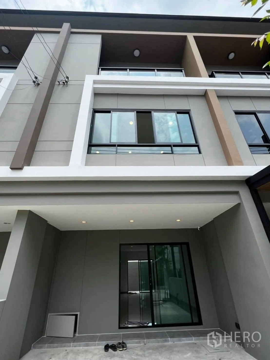 Townhouse for rent in Bang Khen, Bangkok - Modern multi-level townhouse facade with large windows and balcony above carport.