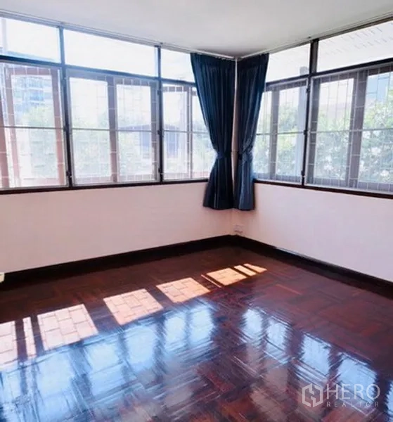 Detached House for rent in Bang Na, Bangkok - Sunlit corner bedroom with wraparound windows and glossy parquet floors.