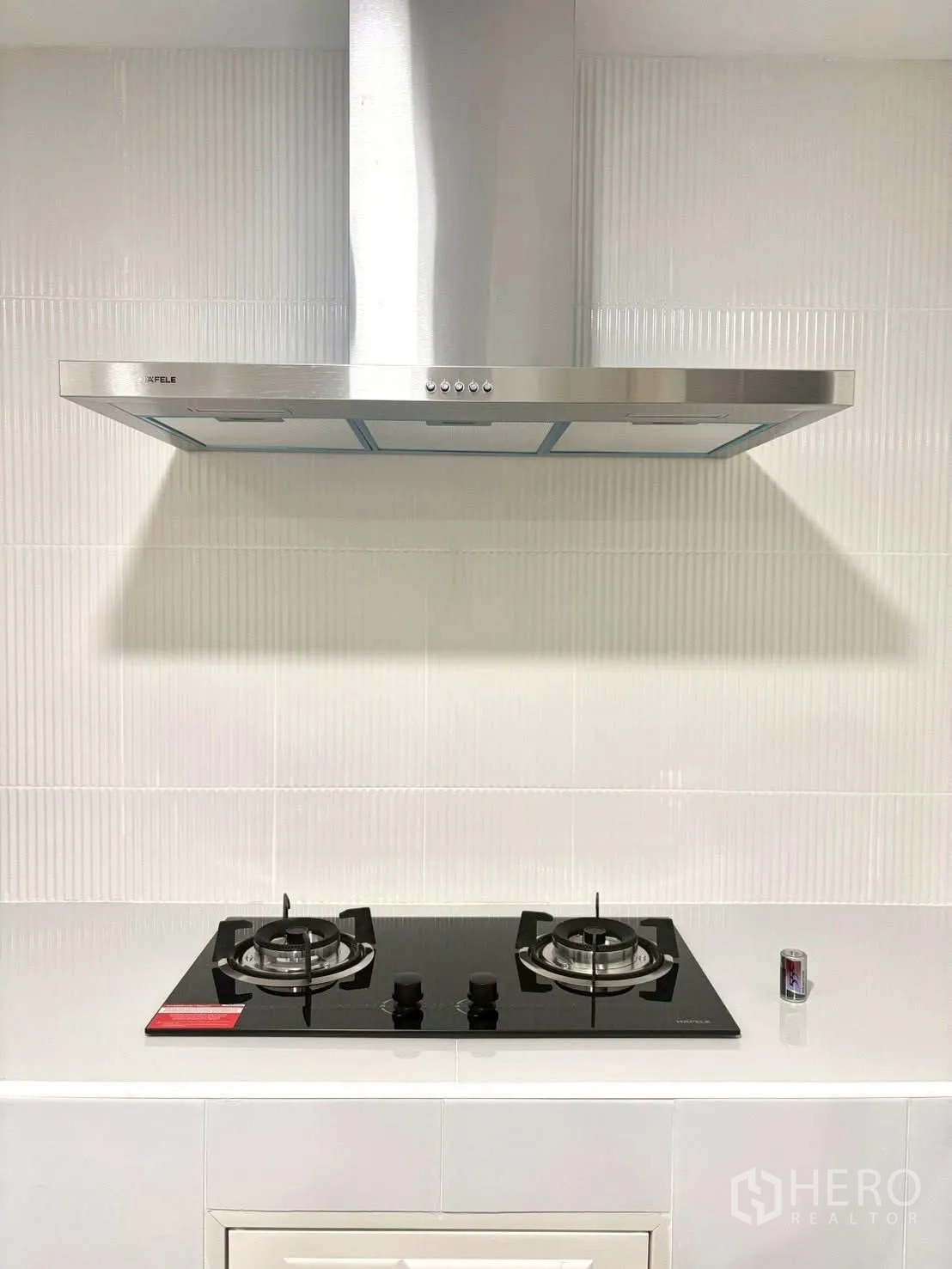Townhouse for rent in Huai Khwang, Bangkok - Close-up of stainless range hood and two-burner gas hob on white countertop.