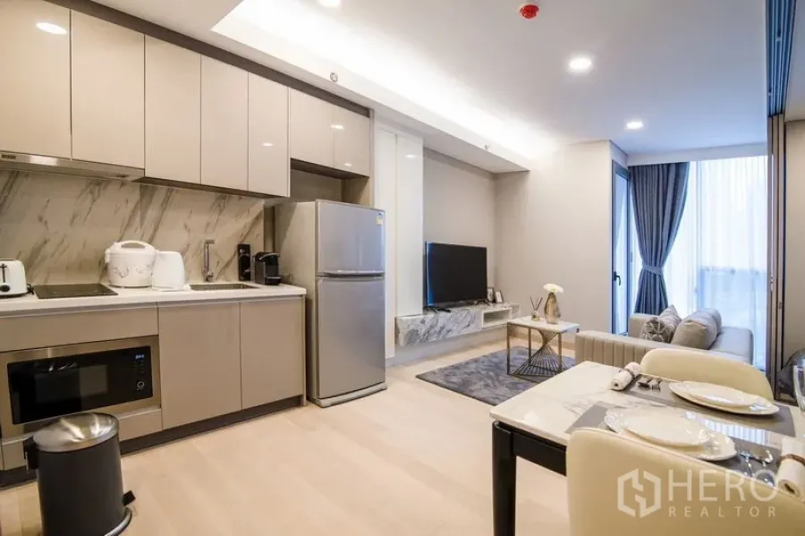Condominium for rent in Khlong Toei, Bangkok - Fitted kitchen with glossy cabinetry, marble backsplash and an adjacent dining area.