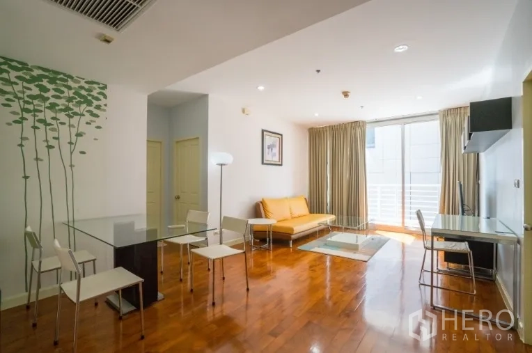 Condominium for rent or sale in Khlong Toei, Bangkok - Open-plan lounge with large sliding doors to the balcony and a dining set.