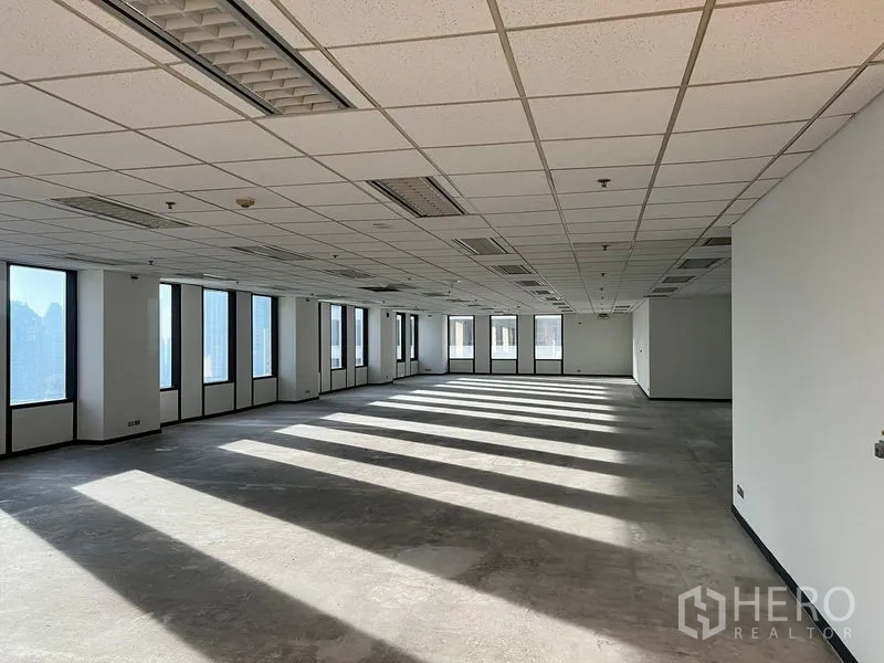 Office Space for rent in Khlong Toei, Bangkok - Unfurnished office space with rows of tall windows, suspended ceiling, lighting panels and air‑conditioning vents, filled with natural light.