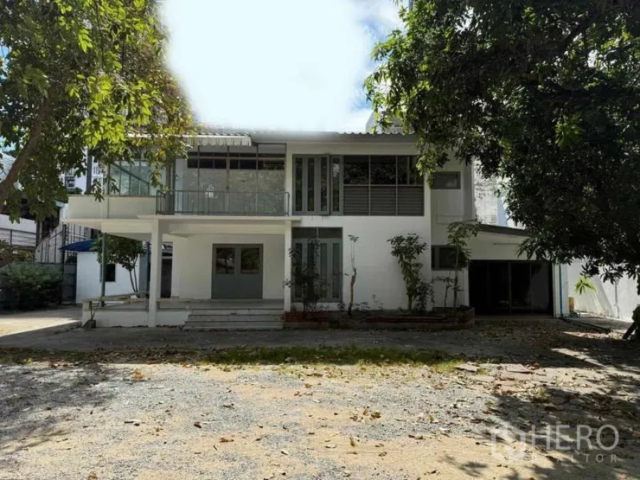 Detached House for rent in Watthana, Bangkok - Front elevation of the detached house with wide gravel driveway and garden.