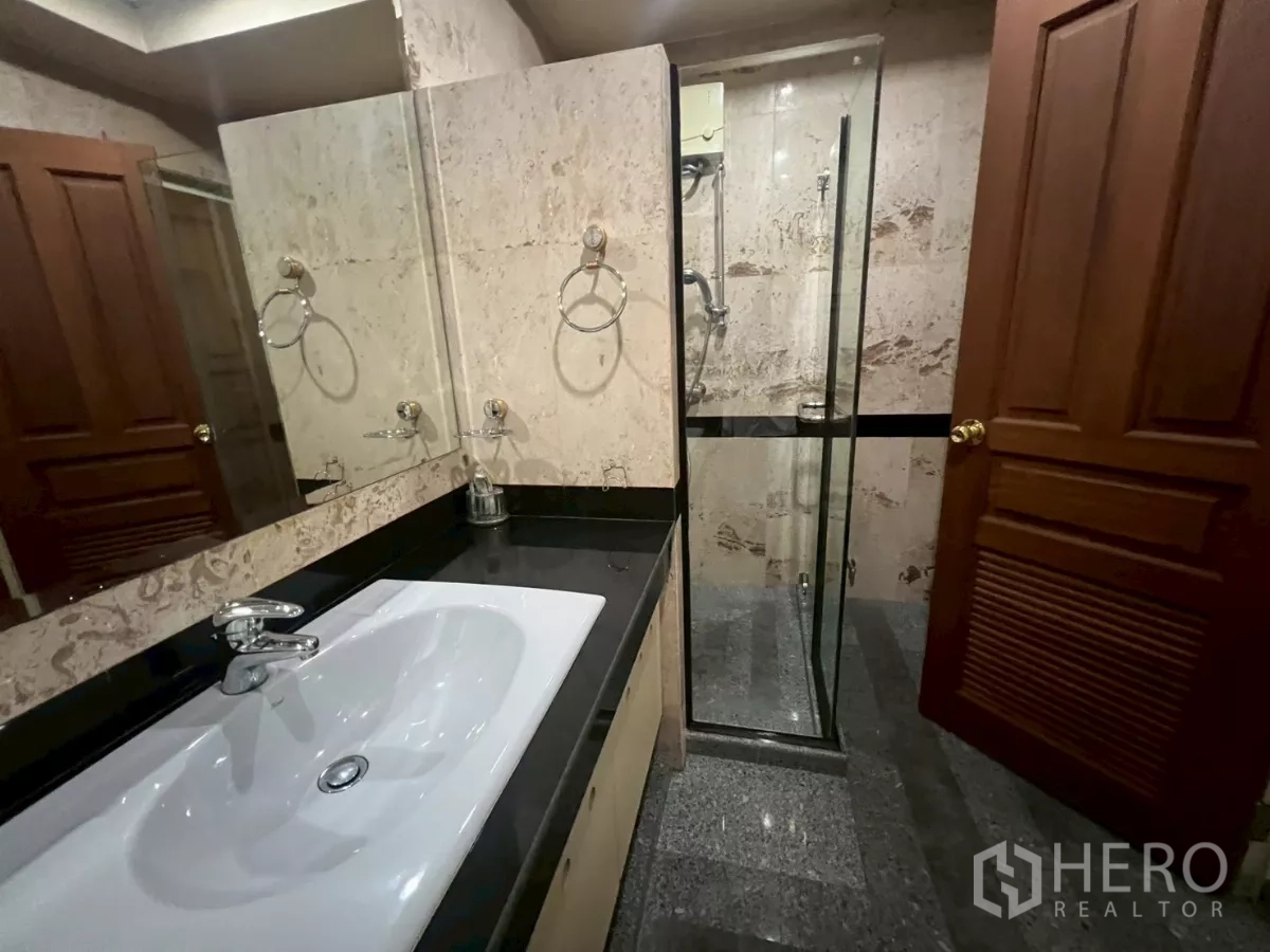 Shophouse for rent in Bang Rak, Bangkok - Bathroom with large vanity, mirror and glass-enclosed shower.