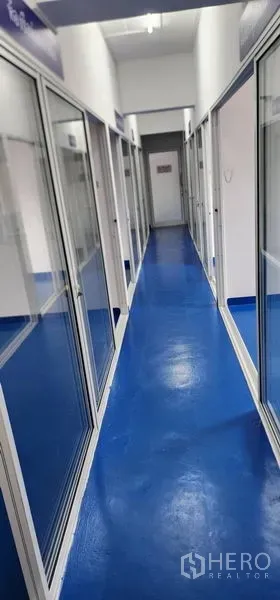 Warehouse for rent in Bueng Kum, Bangkok - Bright corridor with blue epoxy floor and glass-partitioned rooms in a warehouse.