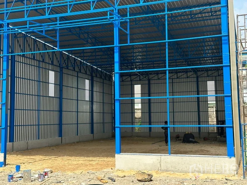 Warehouse for rent in Wang Thonglang, Bangkok - New-build warehouse with blue steel frame, high gabled roof and corrugated metal walls on a concrete base.