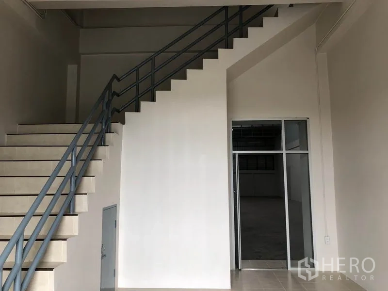 Factory for rent in Pak Kret, Nonthaburi - Entrance foyer with staircase and glass door leading to the warehouse area.