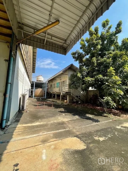 Warehouse for rent or sale in Bang Bon, Bangkok - Service lane beside the warehouse with canopy, auxiliary building and mature trees.
