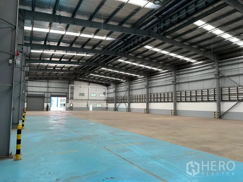Factory for rent in Mueang Samut Prakan, Samut Prakan - Wide warehouse view showing blue-marked work zone and robust steel structure.