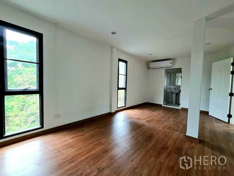 Home Office for rent in Lat Phrao, Bangkok - Bedroom with wood flooring, tall windows, air conditioning, and an ensuite bathroom.