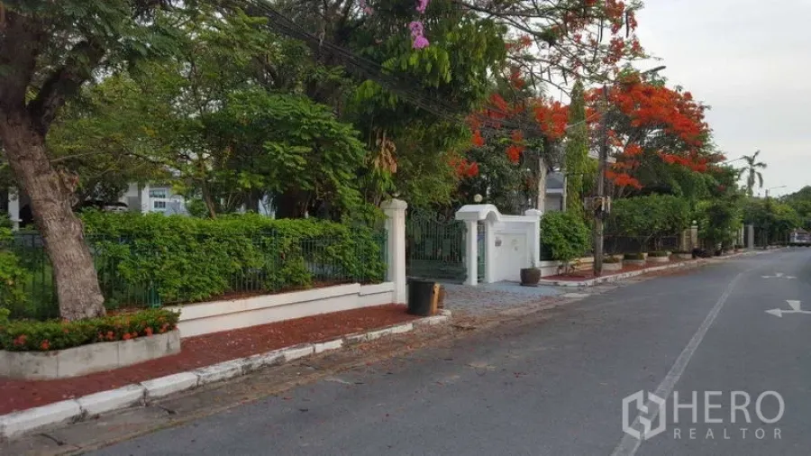 独立式住宅 出租在Bang Phli, Samut Prakan - 安静街道上的房屋前围墙与绿色栅栏。
