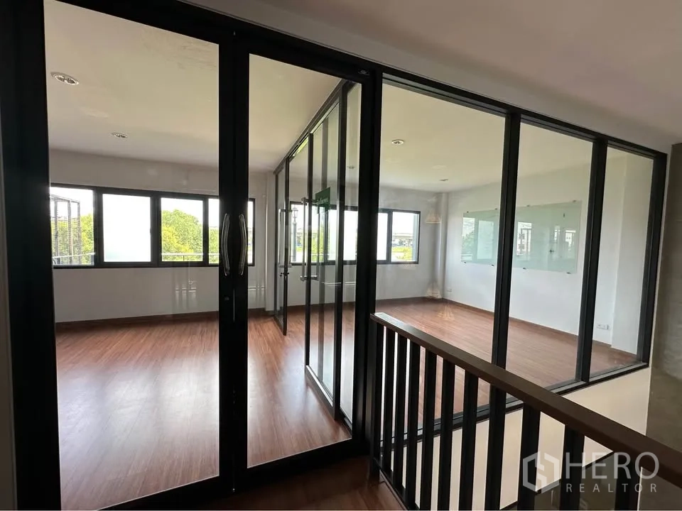Townhouse for rent in Pak Kret, Nonthaburi - Upper-floor landing with black framed glass partitions and views into rooms.