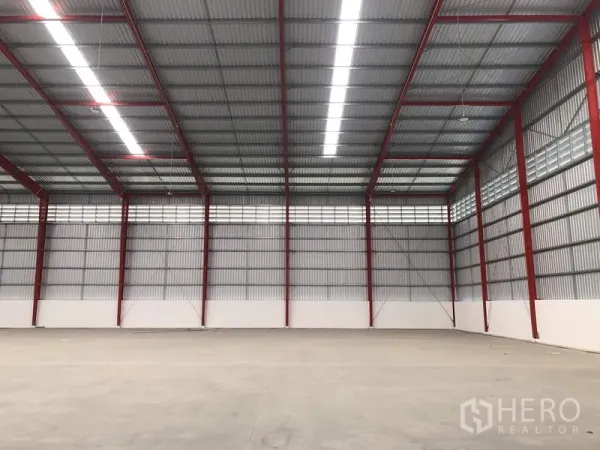 Warehouse for rent in Pak Kret, Nonthaburi - High-clearance warehouse bay with linear lighting and ventilation panels.