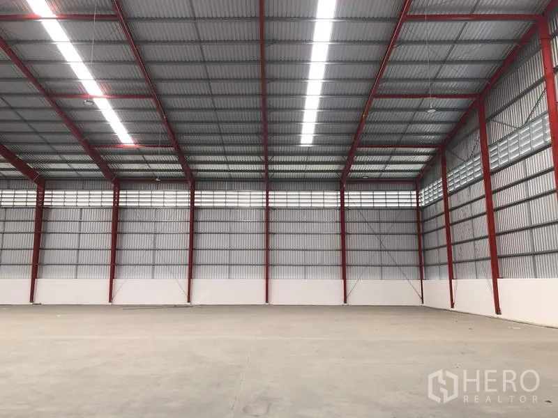 Warehouse for rent in Pak Kret, Nonthaburi - High-clearance warehouse bay with linear lighting and ventilation panels.