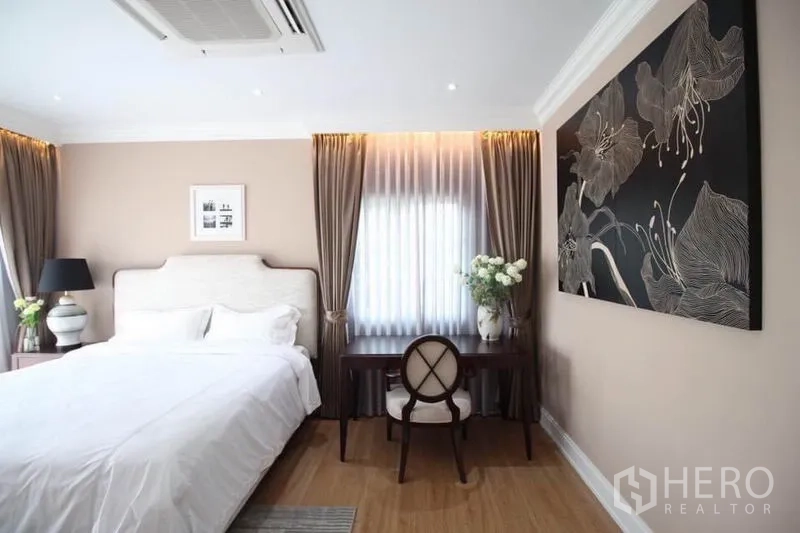 Detached House for rent or sale in Lat Phrao, Bangkok - Bedroom corner with desk and large floral wall art beside a curtained window.