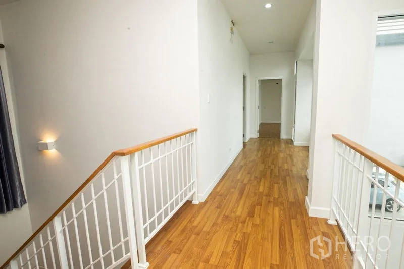 Detached House for rent or sale in Lam Luk Ka, Pathum Thani - Upper hallway with white metal railing and wooden handrail.