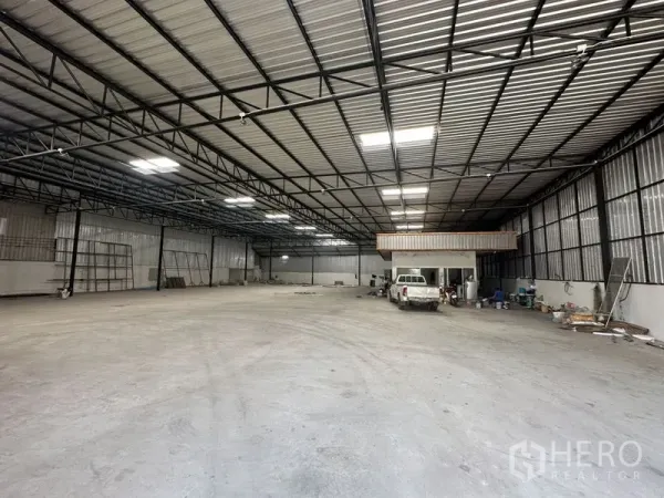 Warehouse for rent in Khlong Luang, Pathum Thani - Spacious warehouse interior with high steel truss roof, skylights, concrete floor and an internal office room.