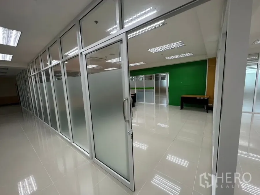 Office Space for rent in Suan Luang, Bangkok - Sliding glass door with frosted panels leading to partitioned office rooms along a polished tile corridor.